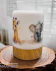 LED-Nachtlicht mit Holzsockel und Giraffen- und Elefant-Motiv, auf Holzrondelle stehend vor weissem Vorhang.