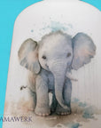 Nahaufnahme von LED-Nachtlicht mit Holzsockel und Elefant-Motiv, vor blauem Hintergrund.