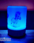 Blau erleuchtetes LED-Nachtlicht mit Holzsockel und Boho-Zebra Motiv, auf holzigem Hintergrund stehend.