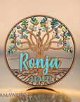Rundes Namensschild von Mamawerk aus Holz, mit blauem Namen und Geburtsdatum aus Acrylglas sowie Lebensbaum mit farbigen Blättern bedruckt.