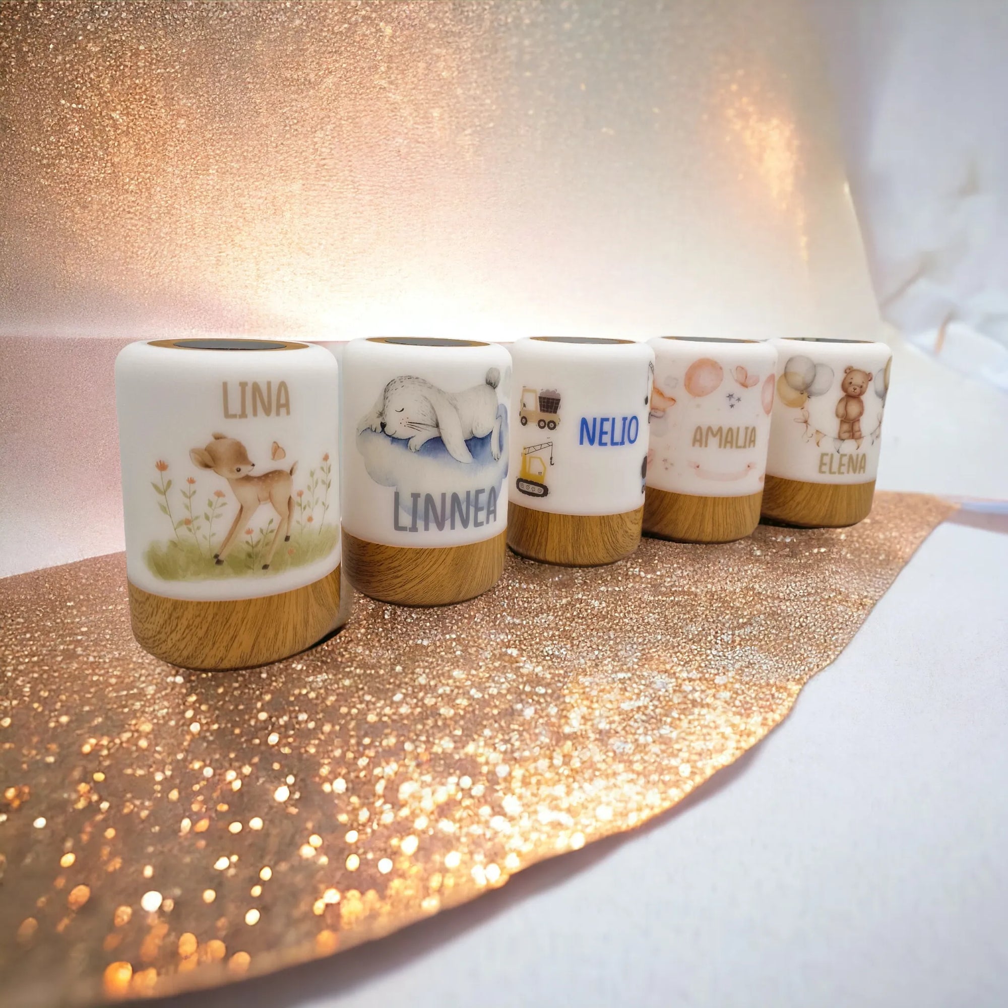 Fünf personalisierbare LED-Nachtlichter mit Boho-Tier-Motiv, auf goldenem, glitzerndem Tischdecklein stehend.
