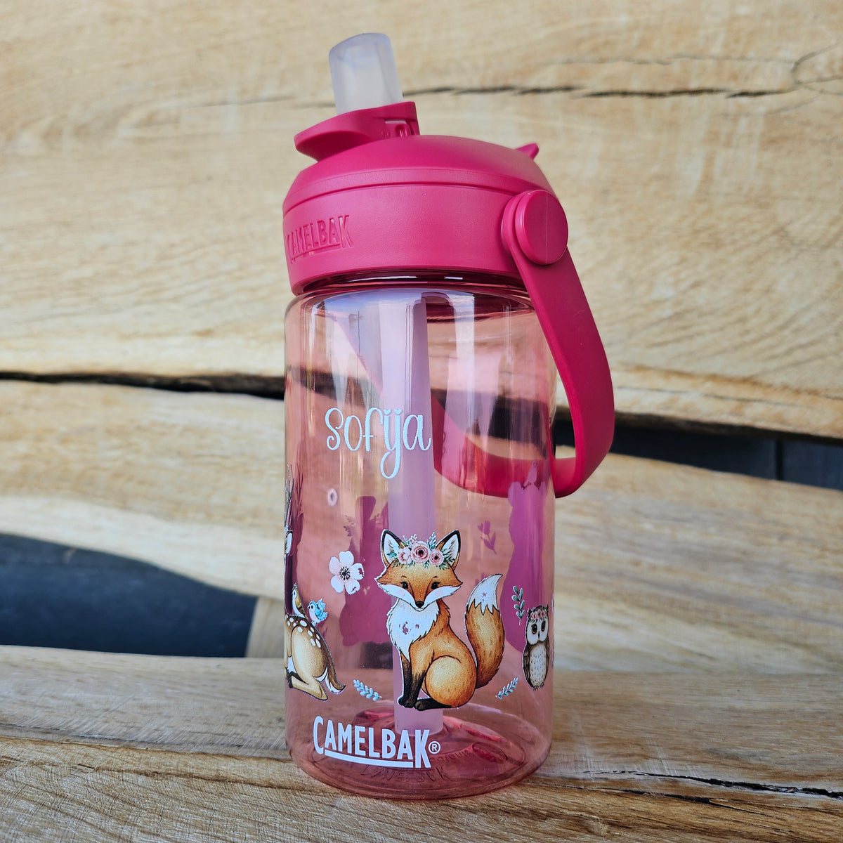 pinke camelbak flasche mit waldtiere und namen personalisiert in den händen eines Mädchens im wald
