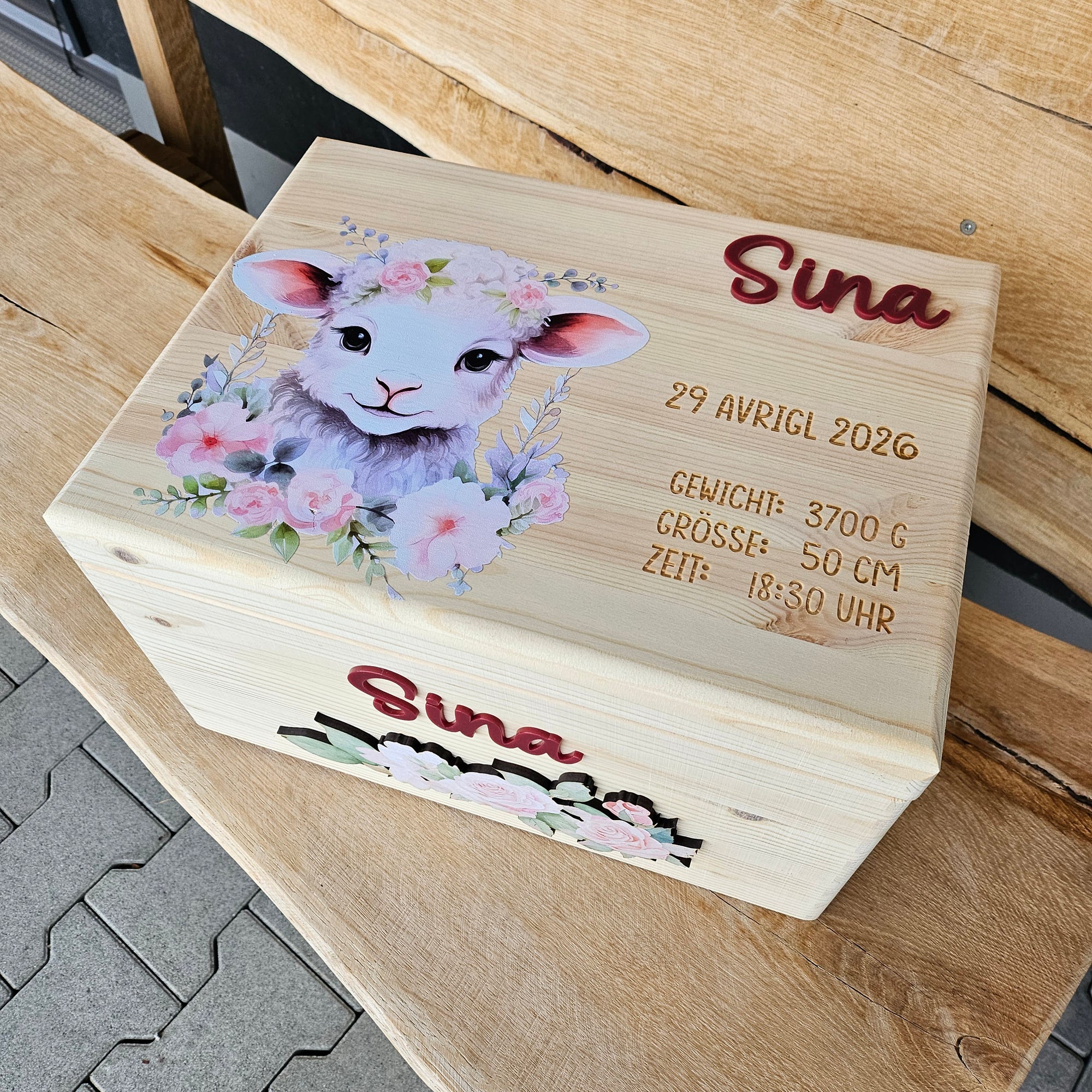 erinnerungskiste schaefchen mit namen und geburtsdaten auf der wiese im frühling