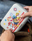 Znünibox Paw Patrol Candy L von Koziol in Sand mit Clipverschluss wird in Rucksack verstaut