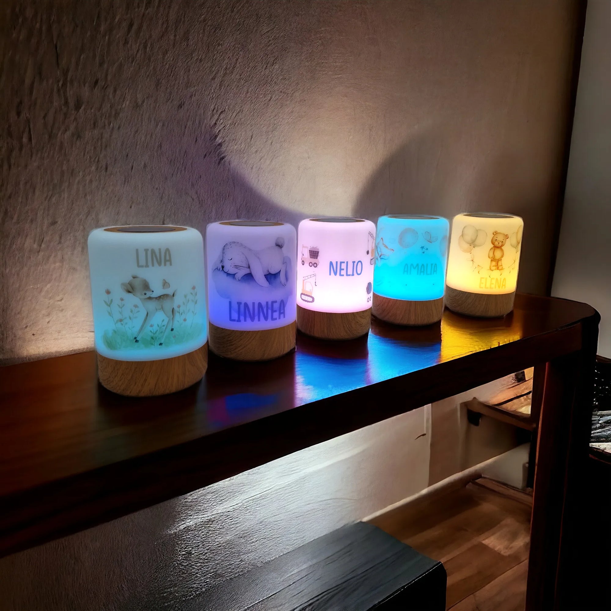 Fünf personalisierbare LED-Nachtlichter mit Boho-Tier-Motiv, in verschiedenen Farben erleuchtet, auf Sideboard stehend.