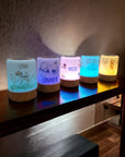 Fünf personalisierbare LED-Nachtlichter mit Boho-Tier-Motiv, in verschiedenen Farben erleuchtet, auf Sideboard stehend.
