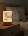 Personalisierteres LED-Nachtlicht mit Holzsockel und Giraffen- und Elefant-Motiv.