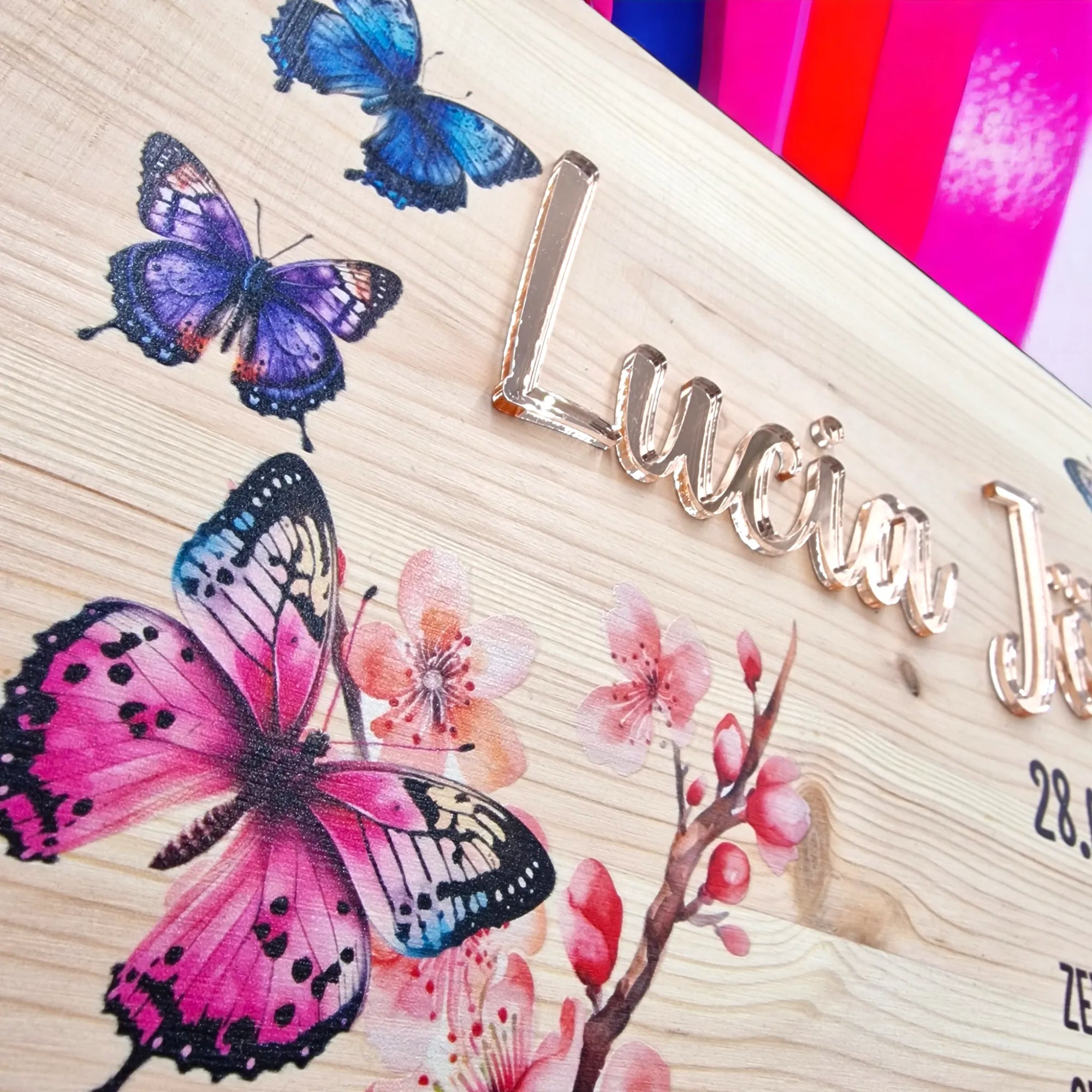 Nahaufnahme von Erinnerungskiste mit Schmetterlingen und Blüte auf Deckel sowie personalisiert mit Namen und schwarzen Geburtsdaten.