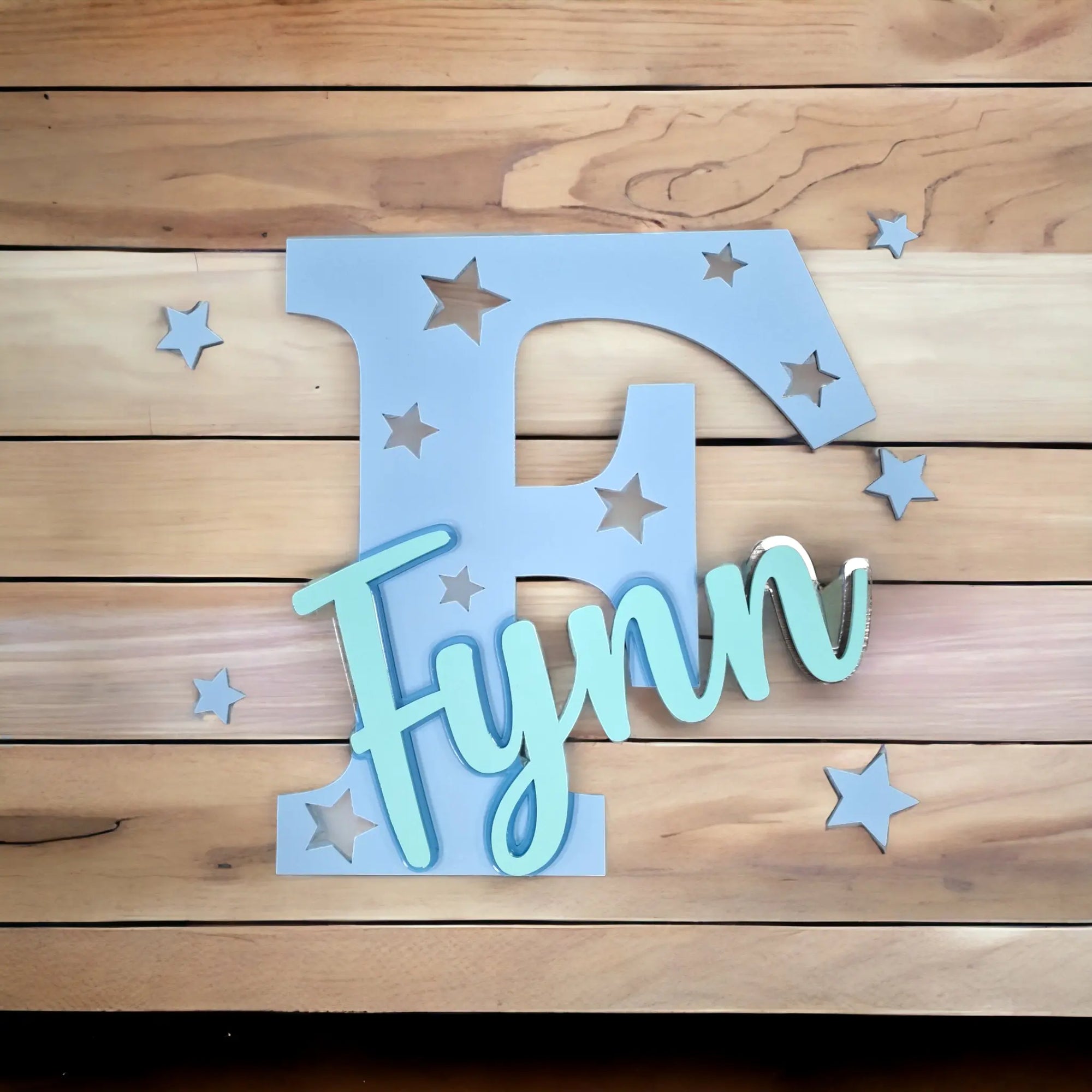 Stehende Namensdekoration aus blauem Acrylglas, mit Buchstaben und türkisem Namen personalisiert.