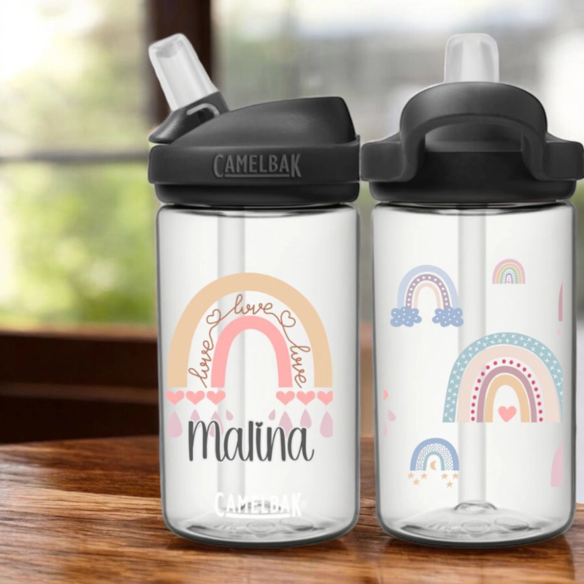 Camelbak Kinder Trinkflasche Regenbogen. Clear weisse eddy Camelbak Trinkflasche für Kinder, mit Boho Regenbogen-Motiv und mit Namen personalisiert. Schwarzer Aufsatz mit Strohhalm.