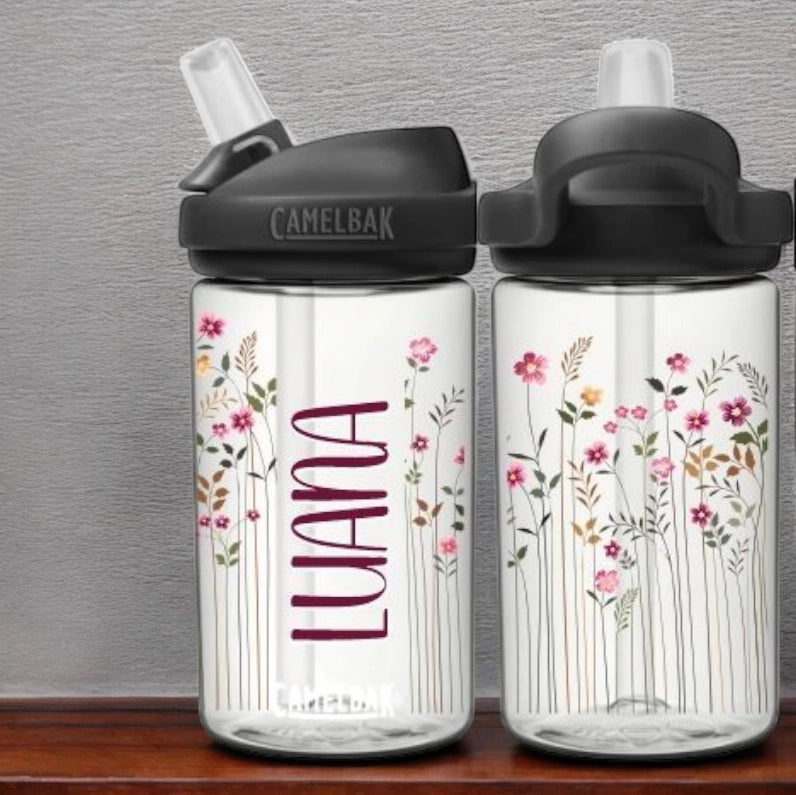 Camelbak Kinder Trinkflasche Blumenwiese. Clear Weisse eddy Camelbak Trinkflasche für Kinder, mit Blumenwiesen-Motiv und mit Namen personalisiert. Schwarzer Aufsatz mit Strohhalm.