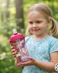 pinke camelbak flasche mit waldtiere und namen personalisiert in den händen eines Mädchens im wald