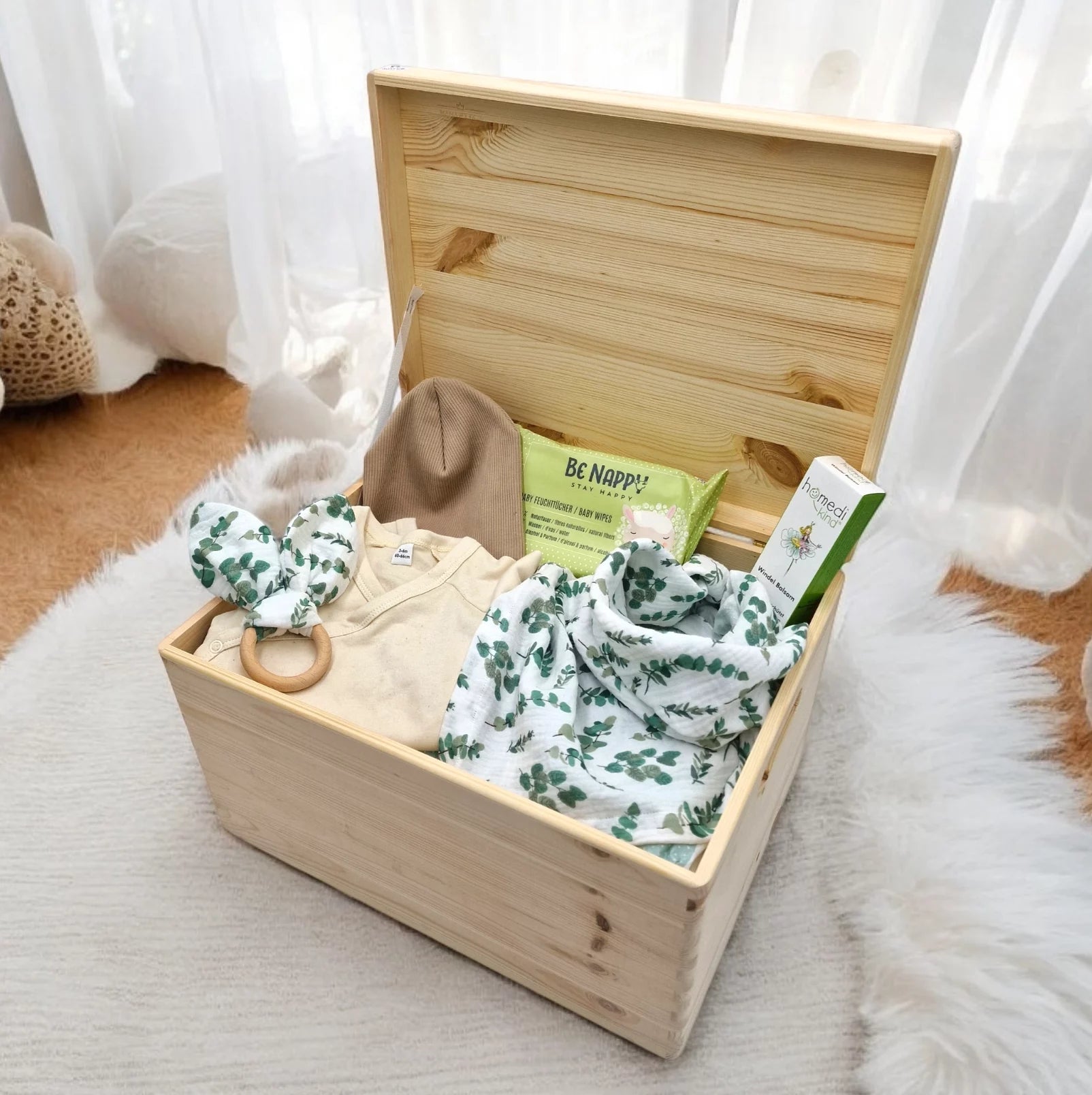 erinnerungskiste befüllt mit babyartikel wie nuschi, beissring, boda, beanie, windelbalsam und windeln von be nappy