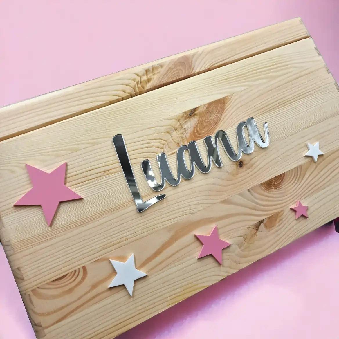 Eine Erinnerungskiste mit pinken und weissen Sternen auf Deckel sowie personalisiert mit Namen und Geburtsdaten. An der Vorderseite ebenfalls mit Sternen dekoriert und mit Namen personalisiert.