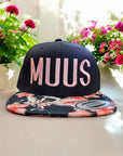 flexfit caps snapback und farbigem Schild mit muus motiv gestickt in rosa mit blumen im hintergrund