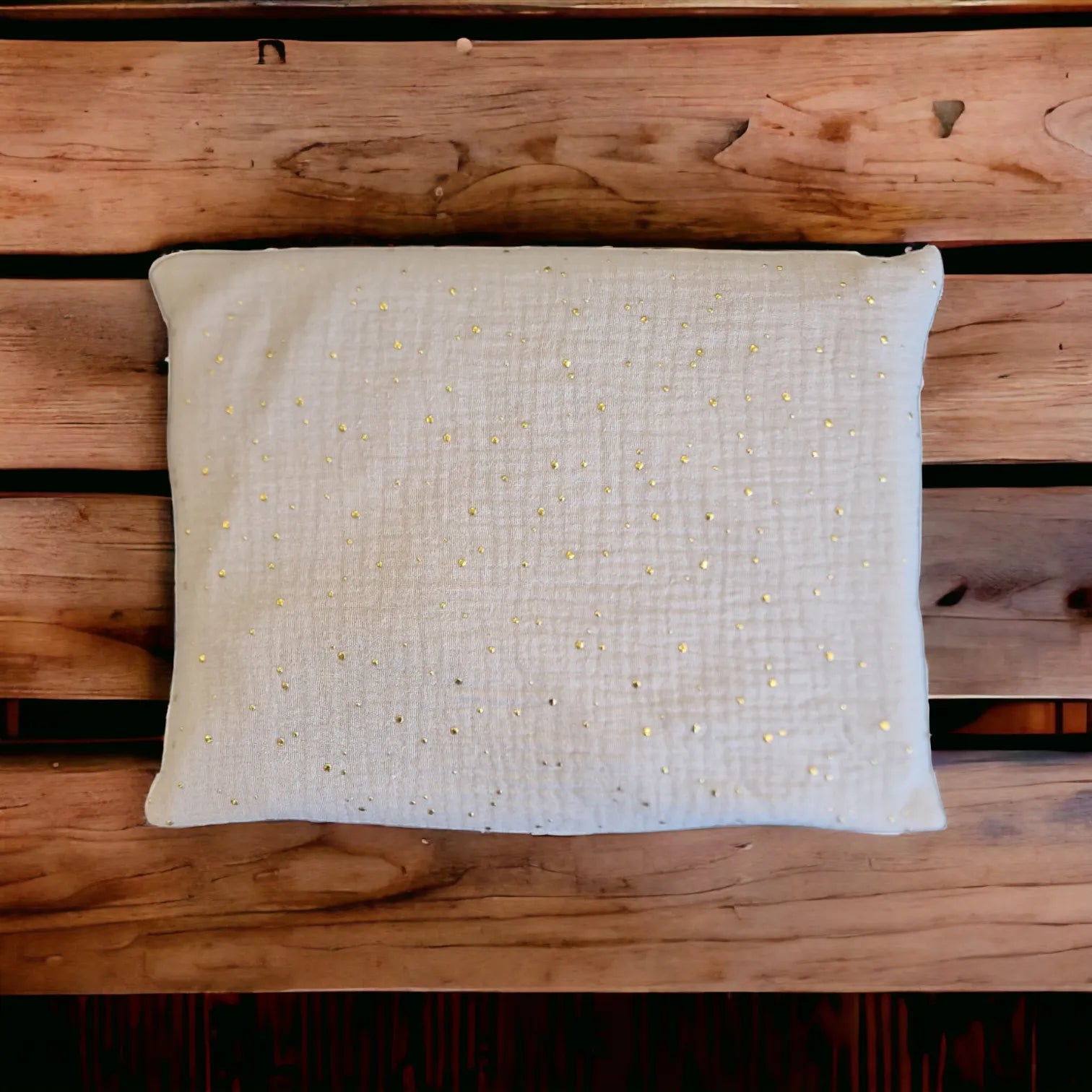 Kirschkernkissen als Wärmekissen, mit beigem Baumwollstoff und goldenen Tüpfchen, auf Holzuntergrund.