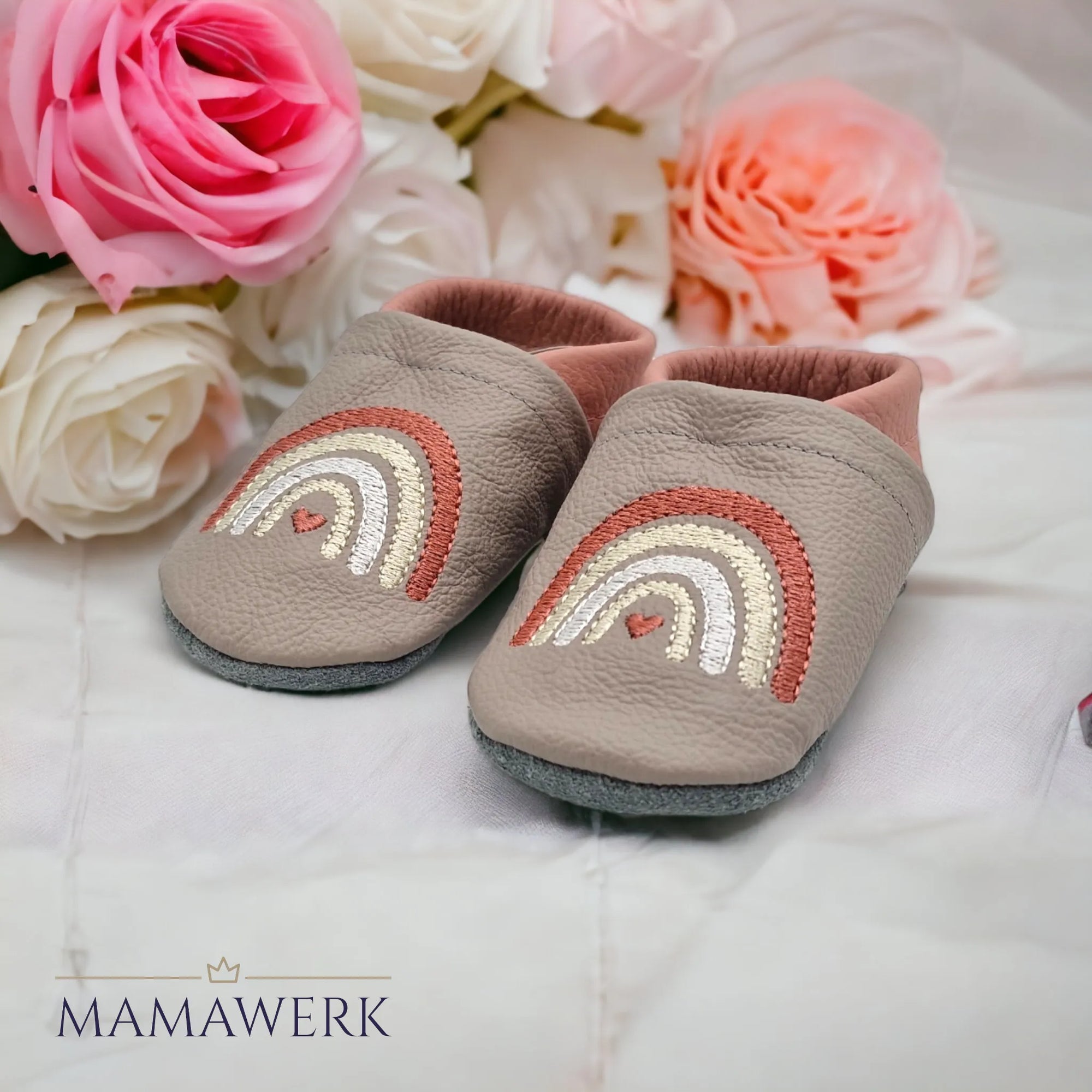 Ein Paar Rosa Lederfinken für Kinder mit beigem Oberleder, welches mit Boho-Regenbogen Motiv bestickt ist. Die Sohle ist aus grauem Leder und rutschfest.