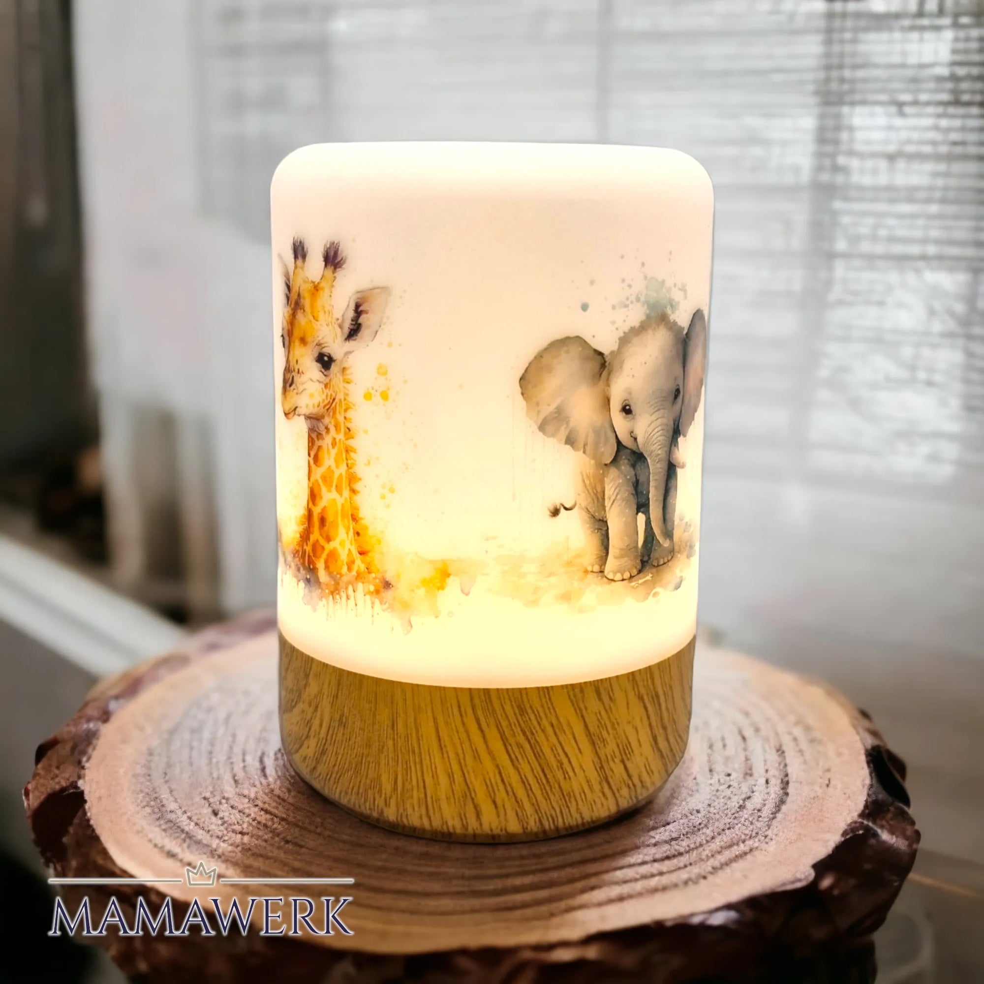 Erleuchtetes LED-Nachtlicht mit Holzsockel und Giraffen- und Elefant-Motiv, mit Namen personalisiert. Auf Holzrondell stehend, vor weissem Vorhang.