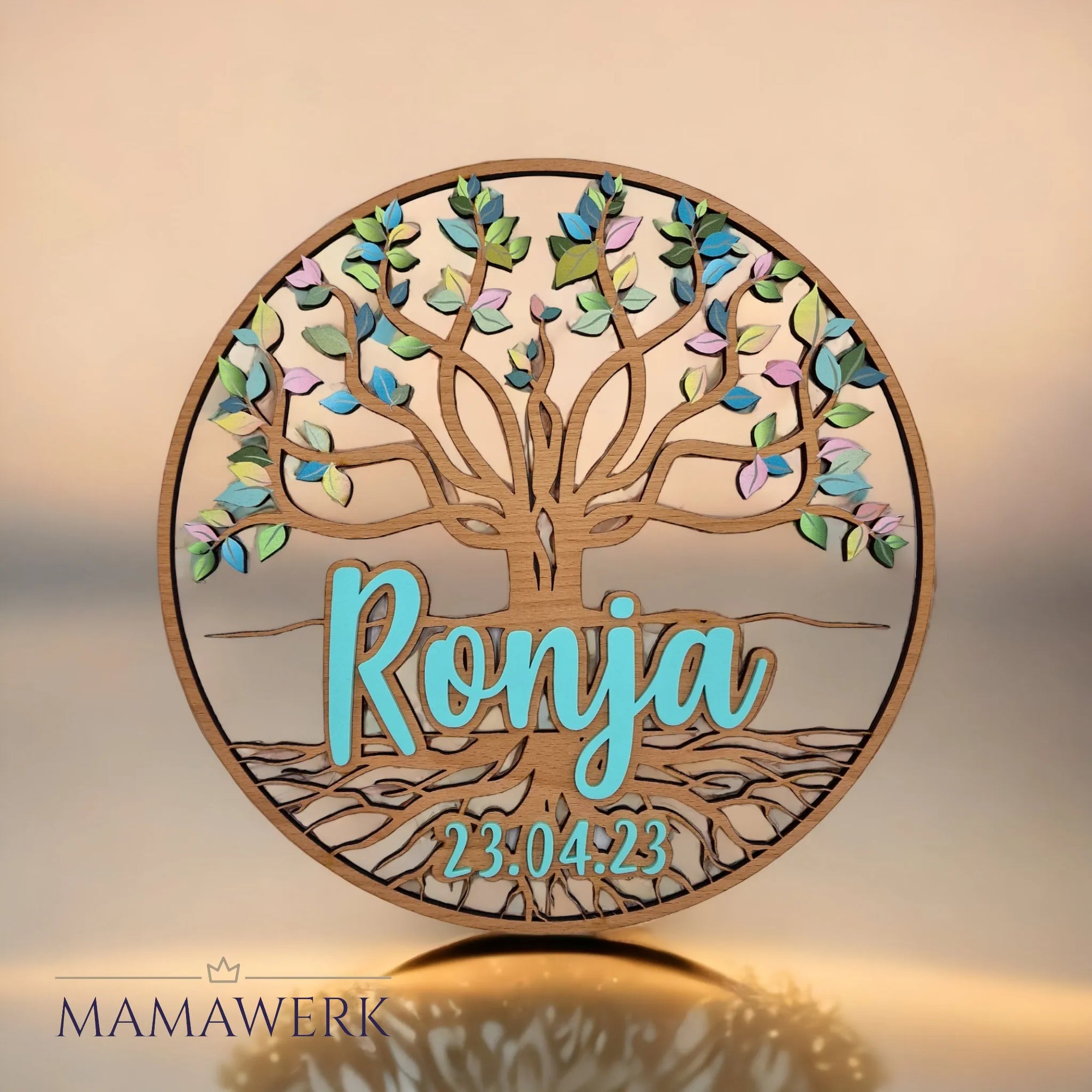 Rundes Namensschild von Mamawerk aus Holz, mit blauem Namen und Geburtsdatum aus Acrylglas sowie Lebensbaum mit farbigen Blättern bedruckt.