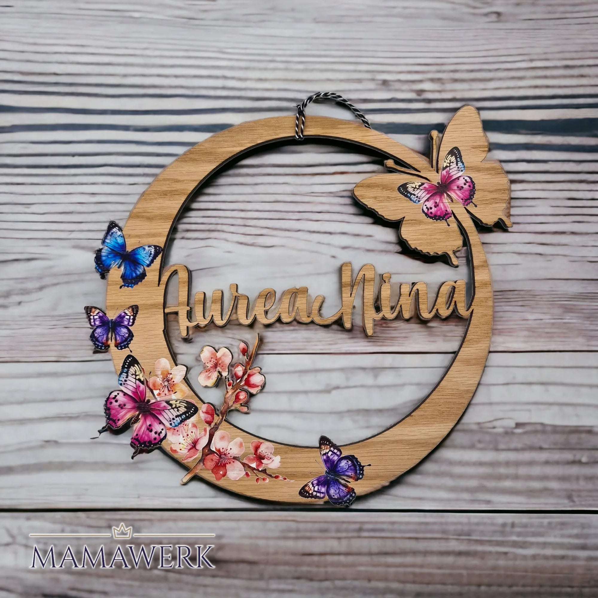 Rundes Namensschild von Mamawerk, aus Holz und mit Schmetterlingen und Blüten bedruckt.