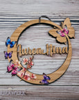 Rundes Namensschild von Mamawerk, aus Holz und mit Schmetterlingen und Blüten bedruckt.
