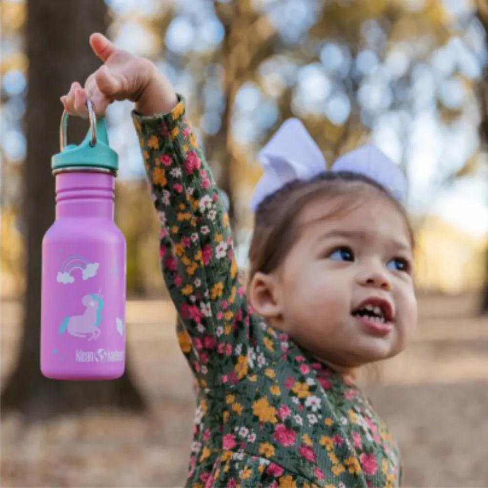 Mädchen hält pinke Klean Kanteen Kinder Trinkflasche mit Einhorn-Motiv und türkiser Verschlusskappe, mit Namen personalisierbar.