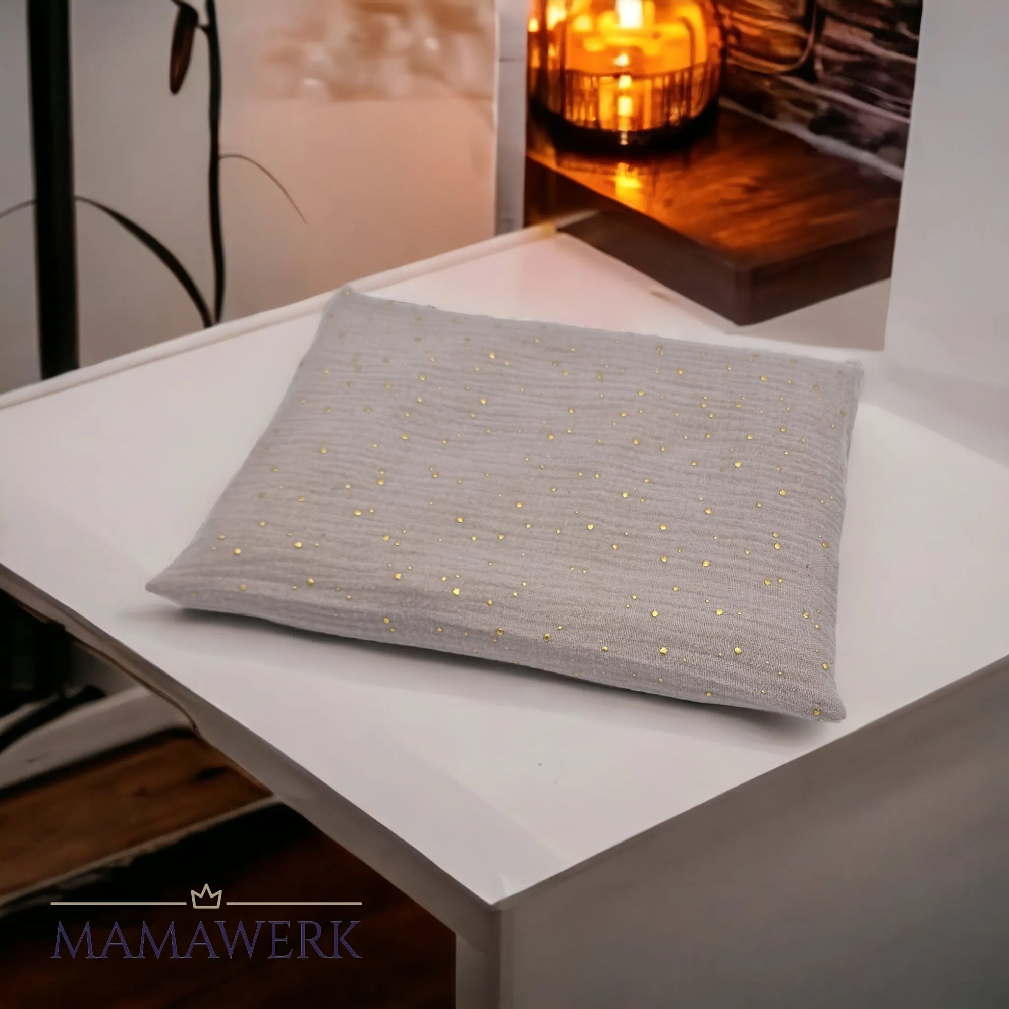 Kirschkernkissen als Wärmekissen, mit beigem Baumwollstoff und goldenen Tüpfchen, auf weissem Tisch.